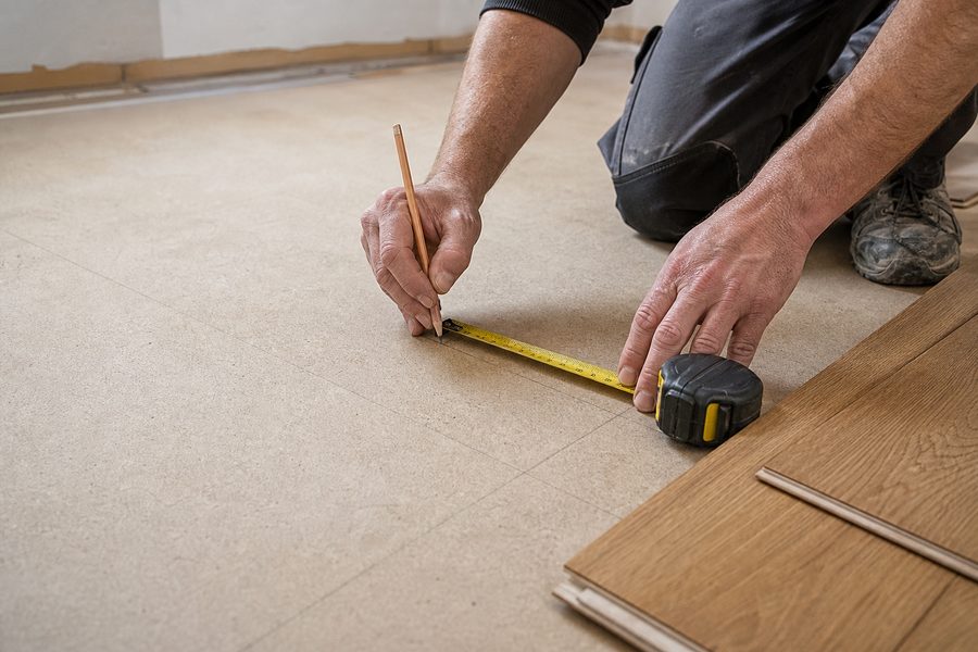 Installer measuring flooring layout with precision